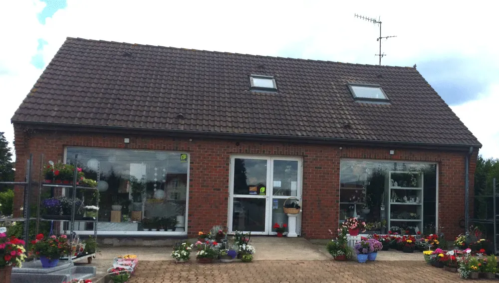 Façade d'un fleuriste en briques avec plantes en pot à l'entrée.