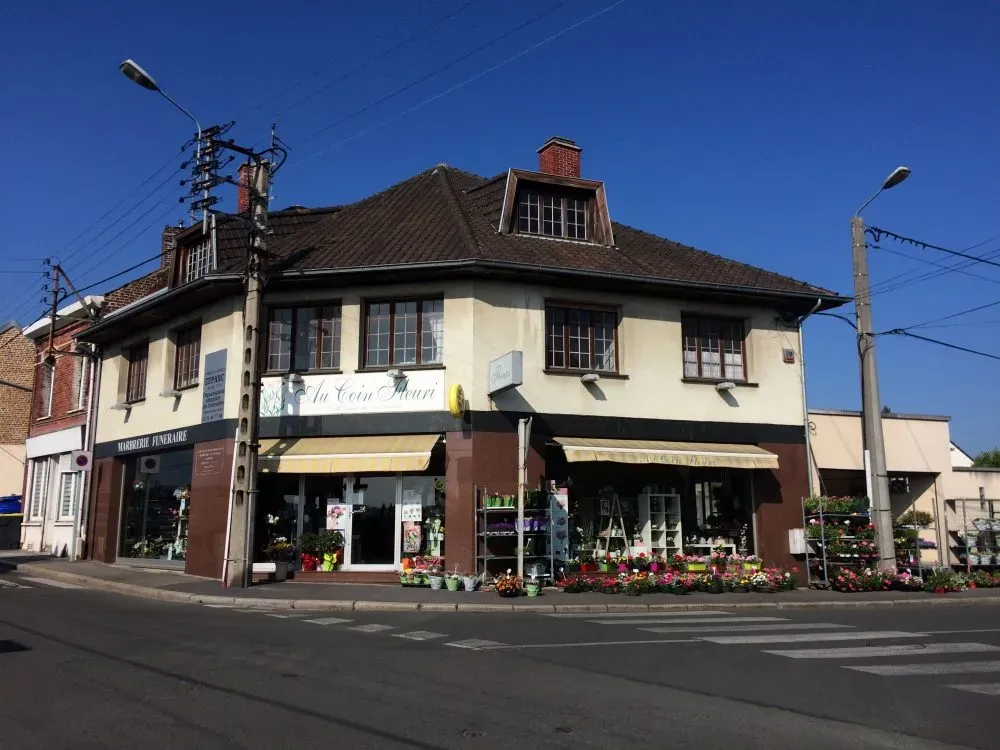 Vue extérieure d'un magasin de marbrerie funéraire en angle de rue.