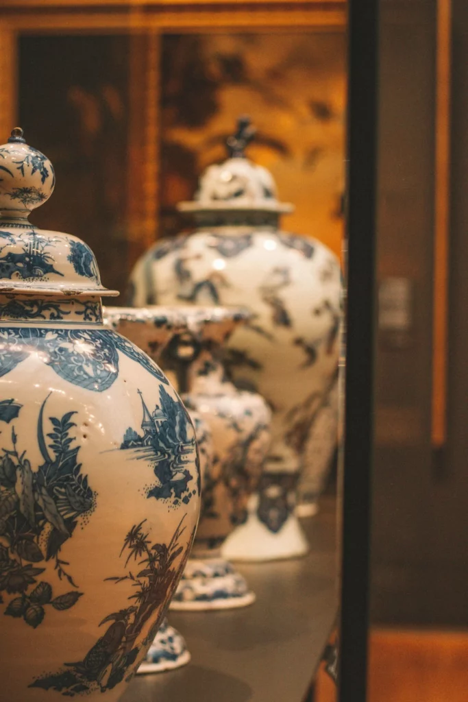 Urnes funéraires en porcelaine bleue et blanche exposées dans une vitrine.
